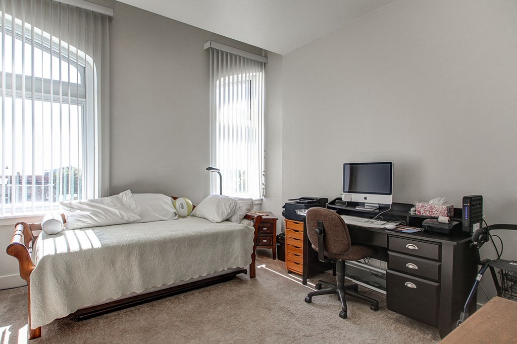 a bedroom with a bed and a desk with a computer