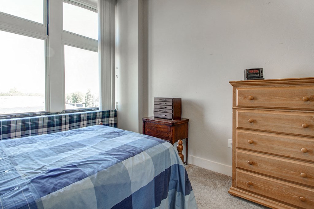 a bedroom with a bed and a dresser and a window