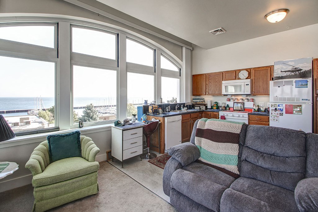 a living room with a couch and a chair and a kitchen with large windows