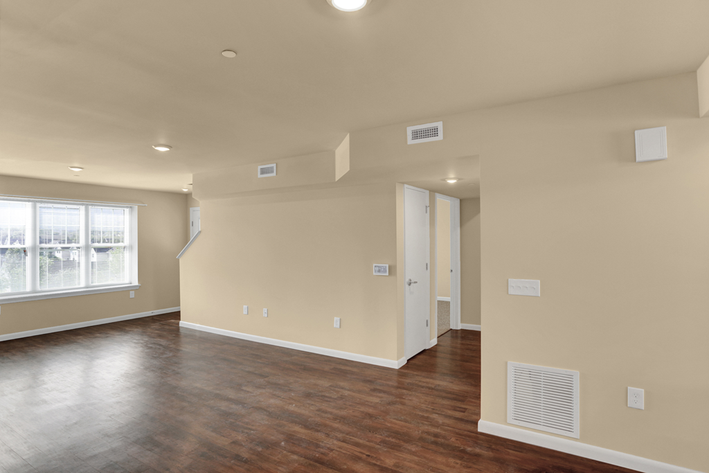 a empty living room with a hard wood floor and white walls