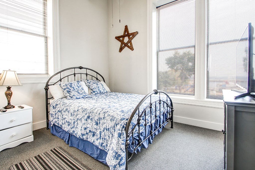 a small bedroom with a bed and two windows