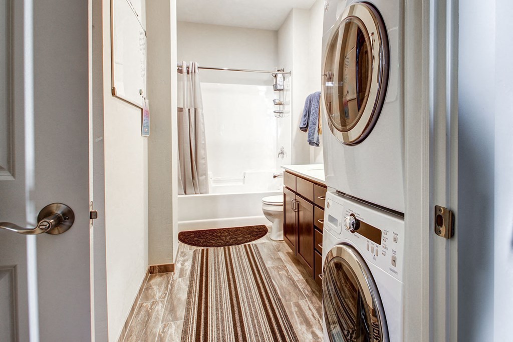 a bathroom with a washer and dryer in it and a tub and sink