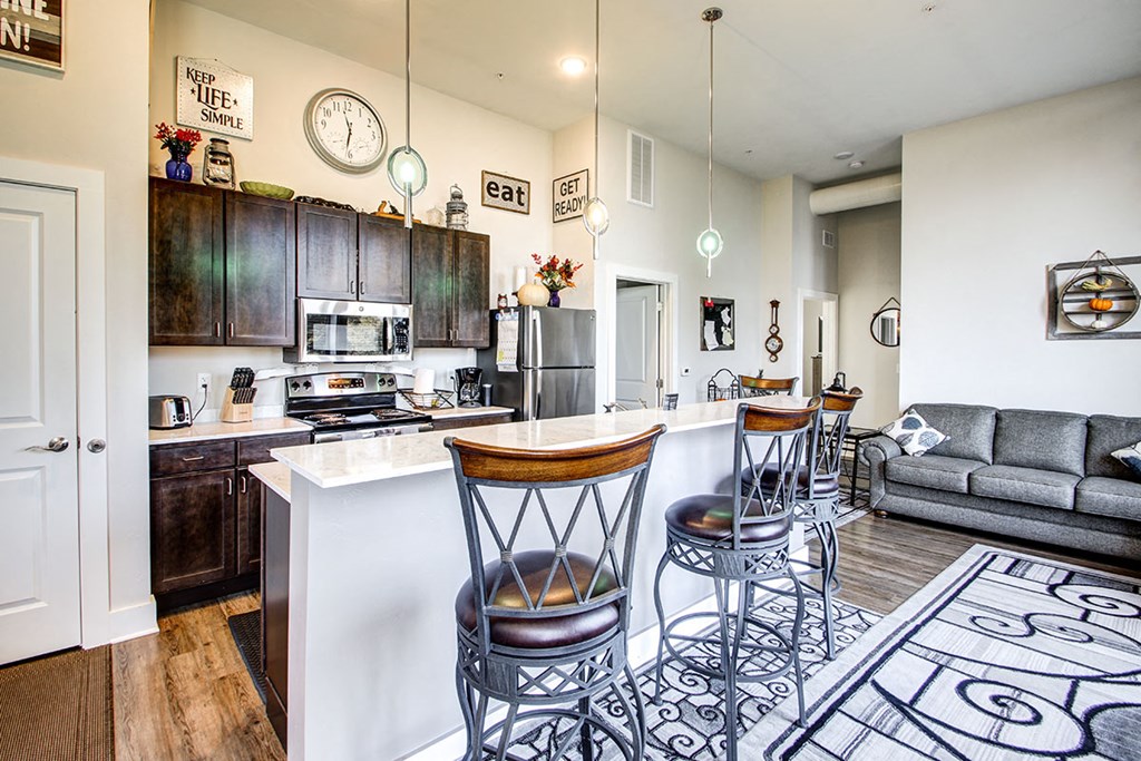 a kitchen and living room with a bar and stools