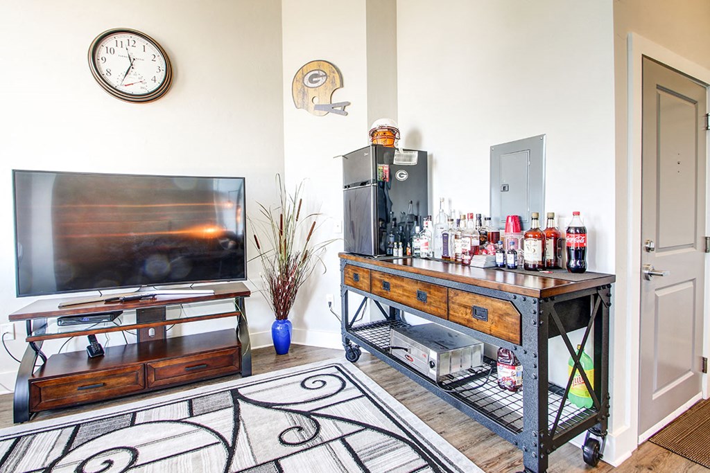 the living room has a bar with a television and a refrigerator