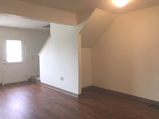 an empty living room with white walls and a wood floor