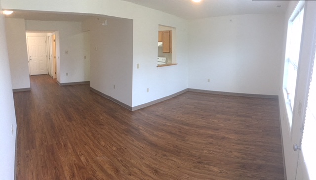 an empty living room with white walls and wooden floors