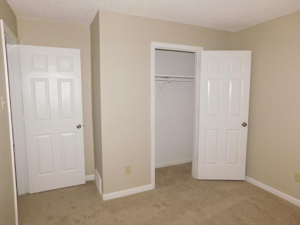an empty bedroom with a closet and two doors