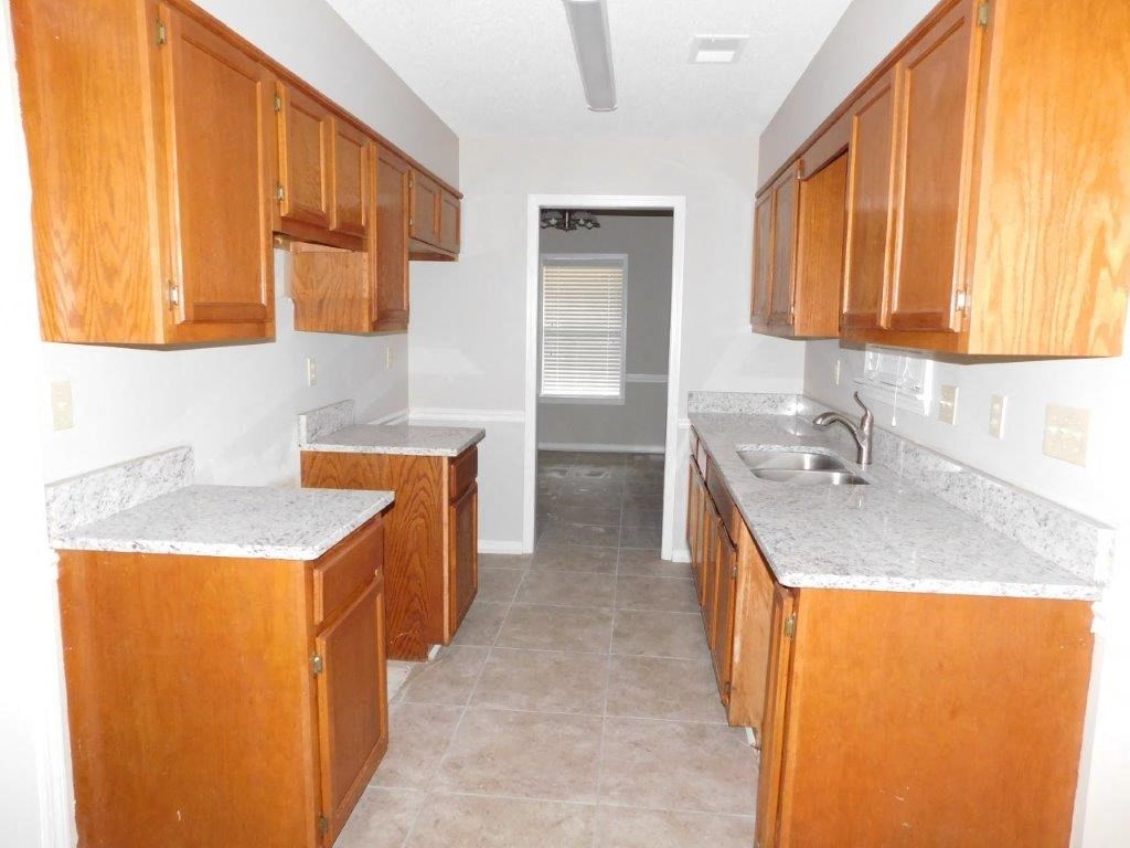 a kitchen with wooden cabinets and marble counter tops