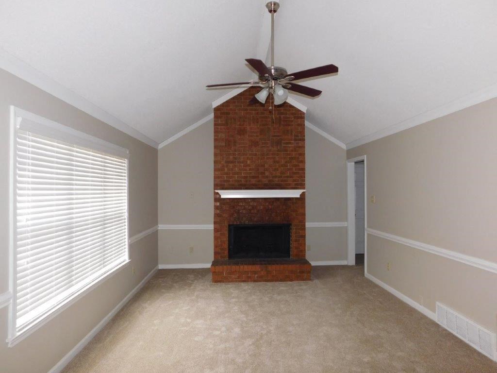 a living room with a brick fireplace and a ceiling fan