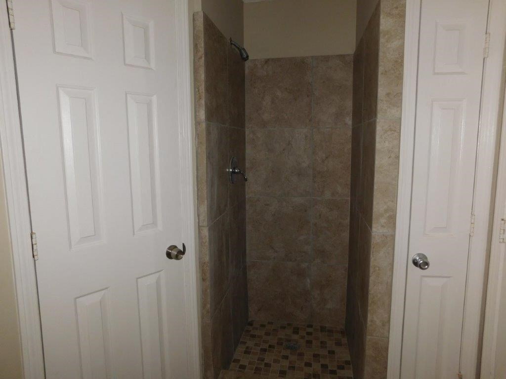 a bathroom with a shower and a white door