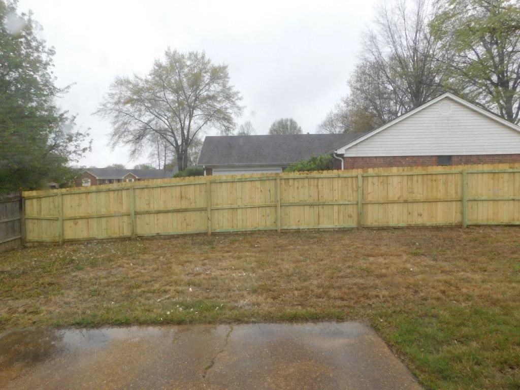 a wooden fence in a yard in front of a house