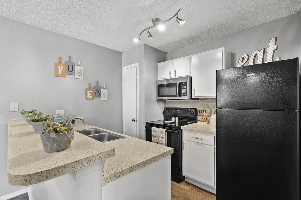 a kitchen with white appliances and a black refrigerator