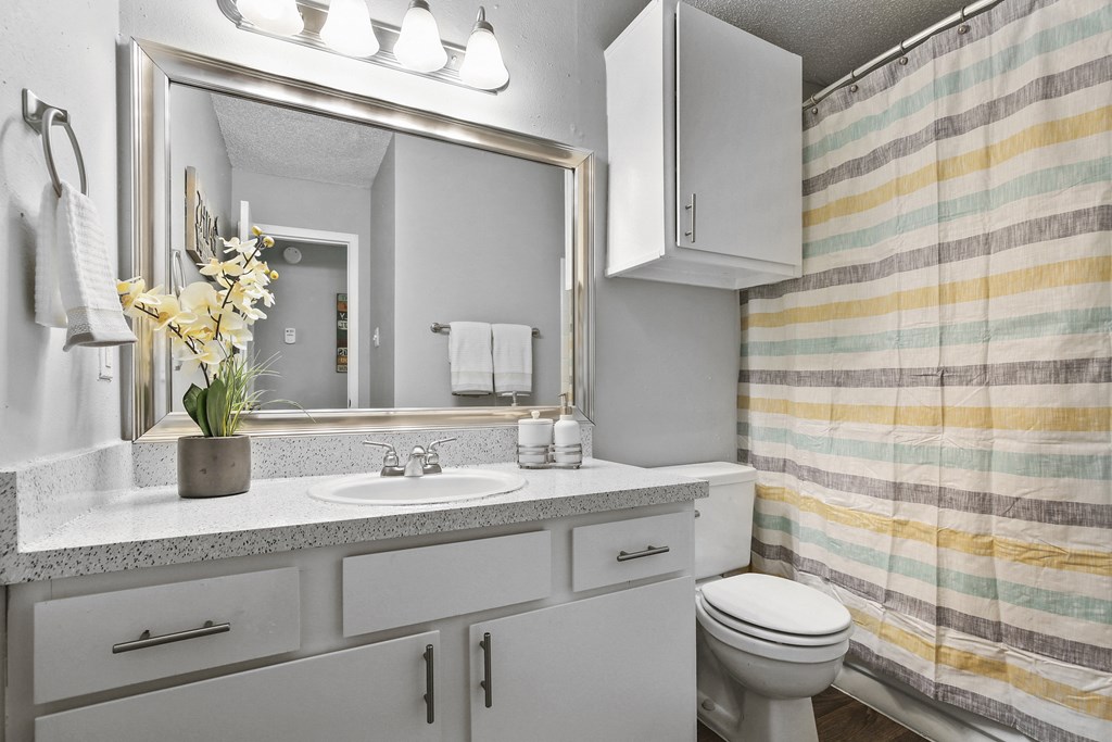 a white bathroom with a striped shower curtain and a toilet