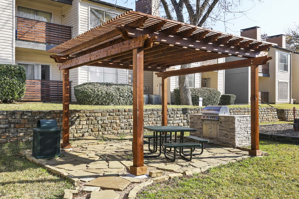 a patio with a picnic table under a wooden pergola