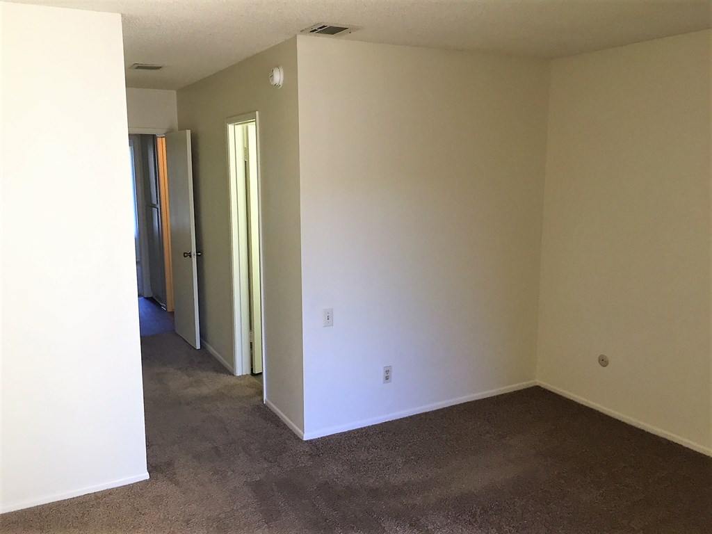 an empty living room with white walls and a carpet
