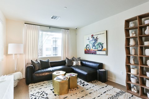 a living room with black leather furniture and a white rug