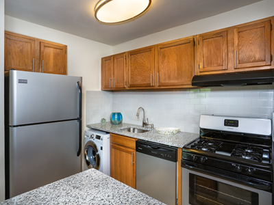 kitchen at Park Greene apartments in Suitland MD with stainless steel appliances, marble countertops, light wood cabinets and washer dryer unit