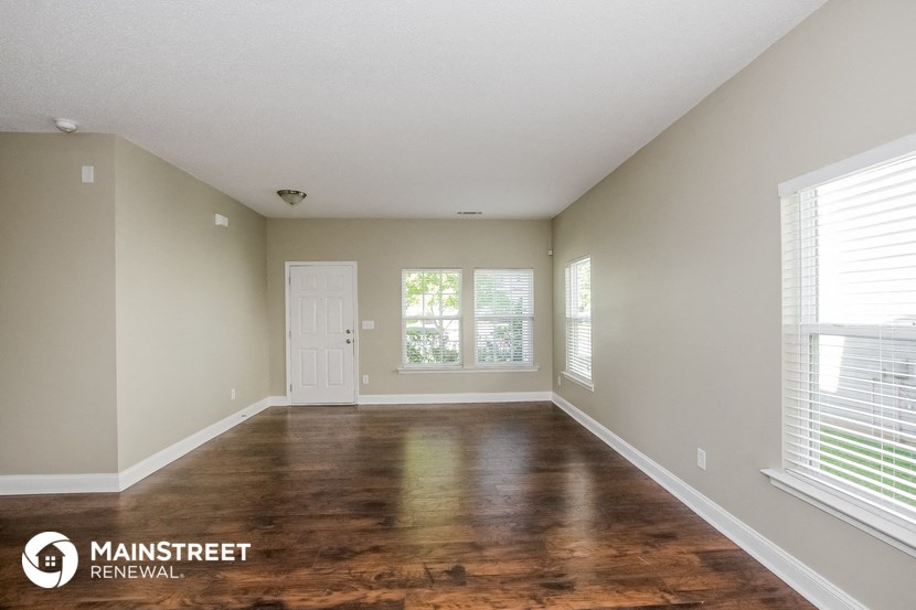 the spacious living room with wood flooring and large windows