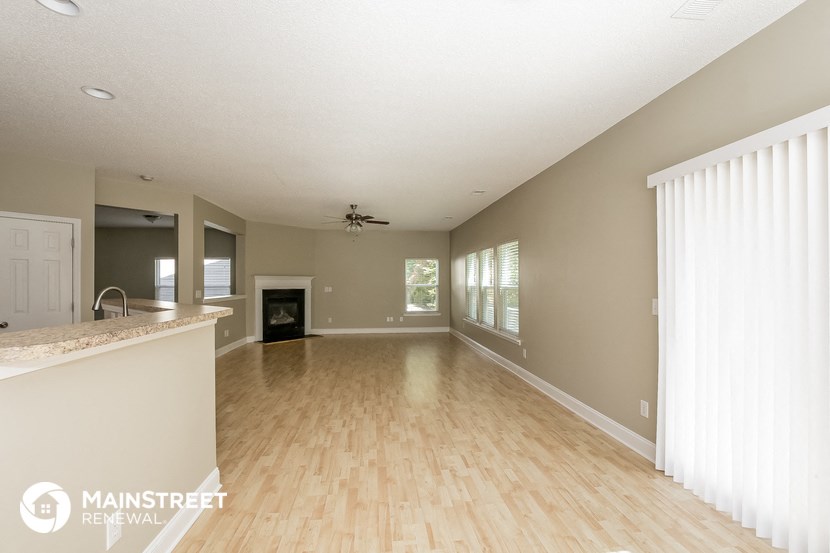 an empty living room with a fireplace and wood flooring