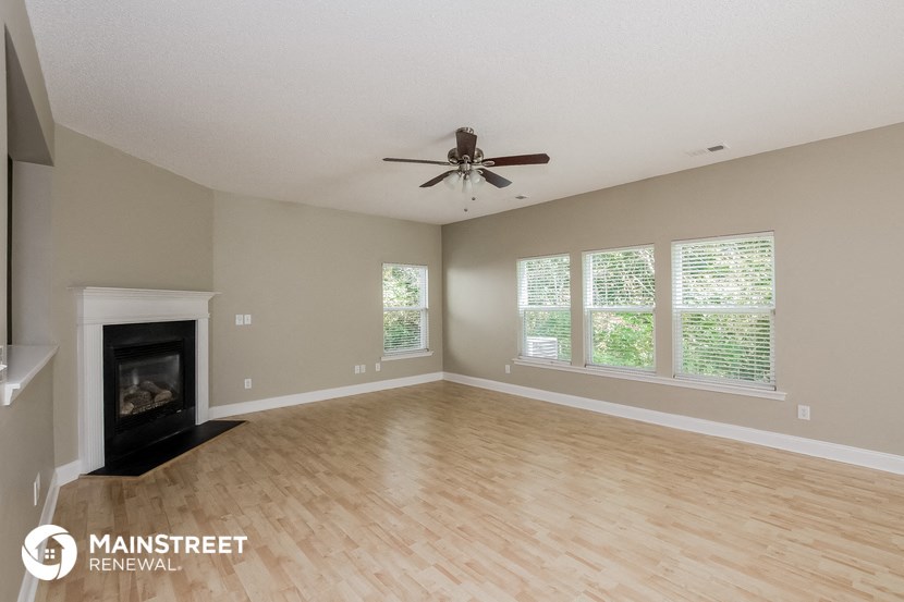 an empty living room with a fireplace and a ceiling fan