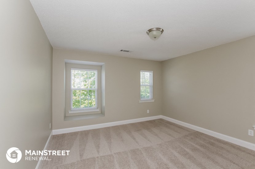 the spacious living room with carpeting and two windows
