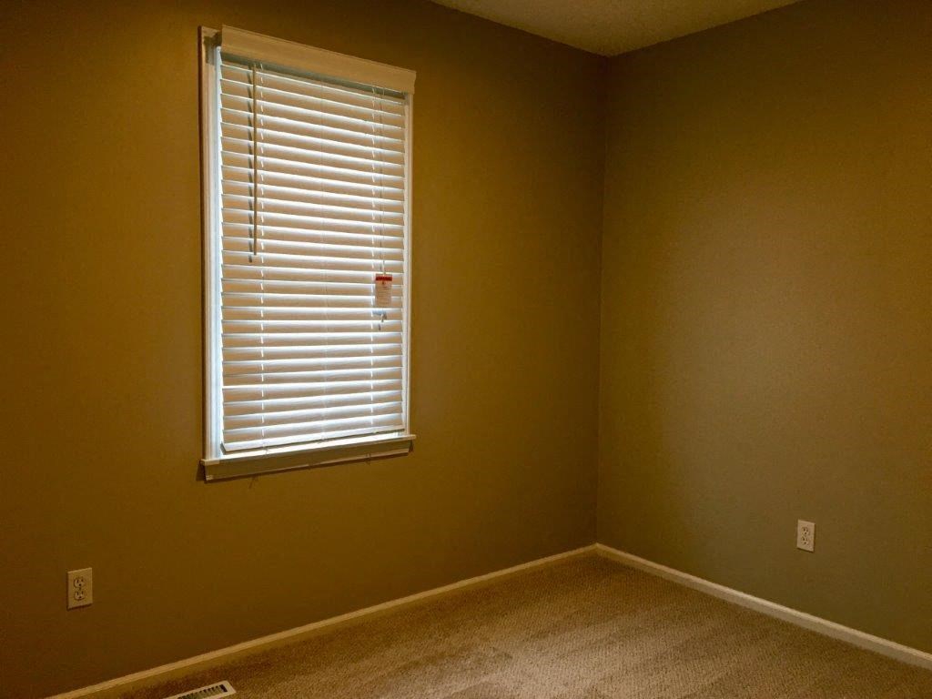 an empty room with a window with blinds