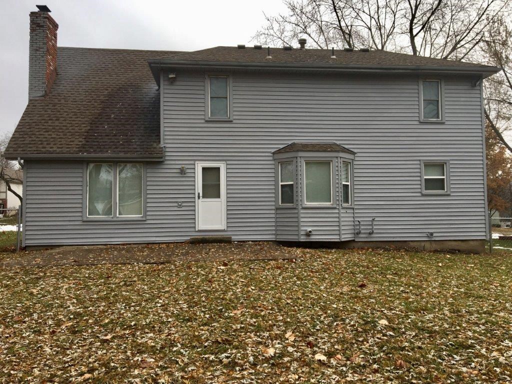 a gray house with a yard with fallen leaves