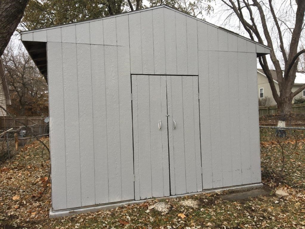 a small shed with two doors in a yard