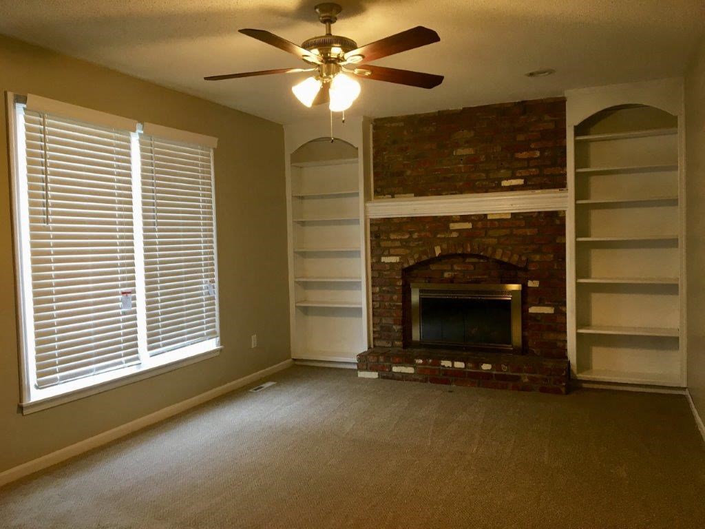 a living room with a fireplace and a ceiling fan