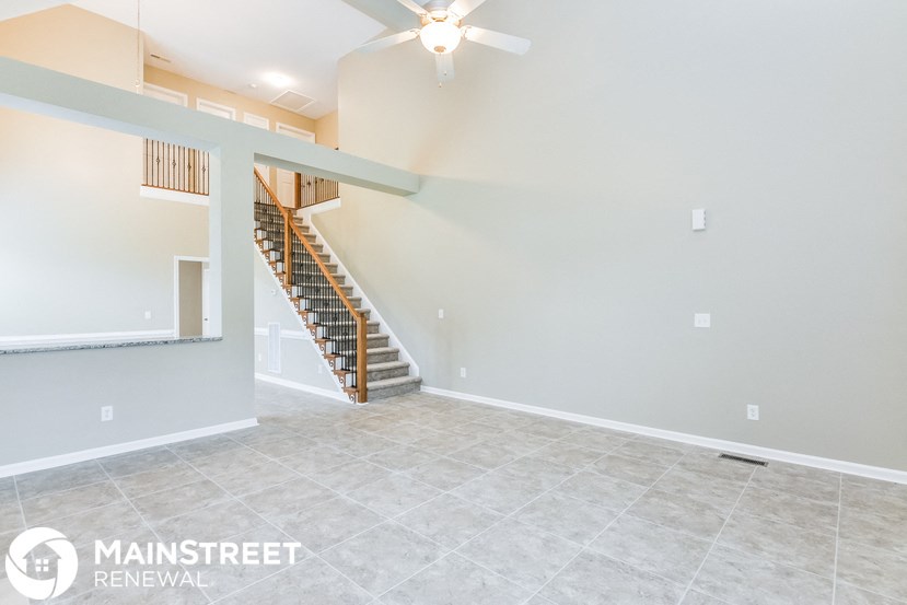 a living room with a staircase and a ceiling fan