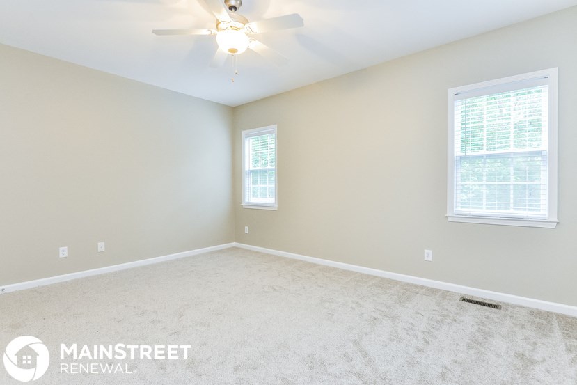 the master bedroom with carpeted floors and a ceiling fan