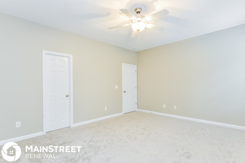 the master bedroom has a carpeted floor and a ceiling fan