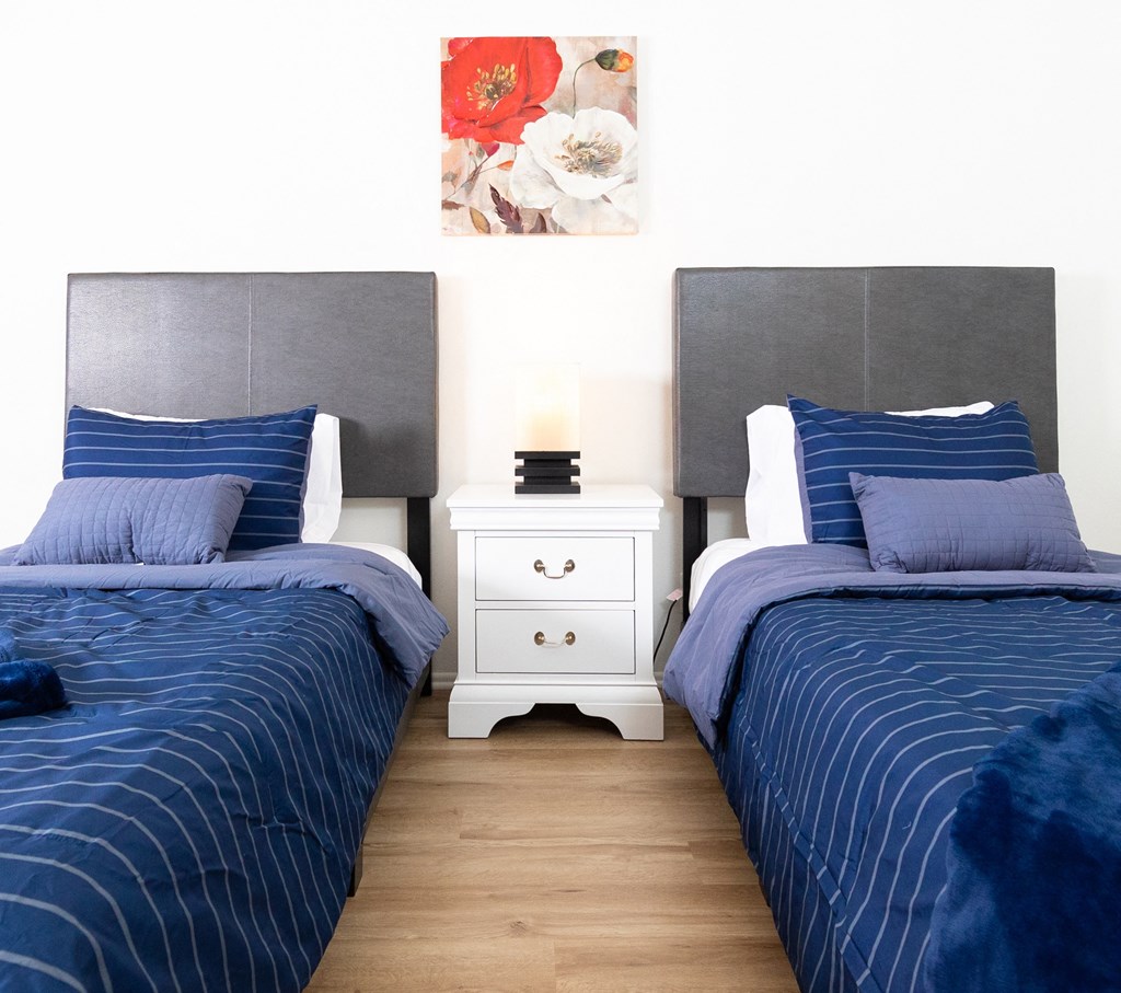 two twin beds with blue comforter and pillows in a room with white