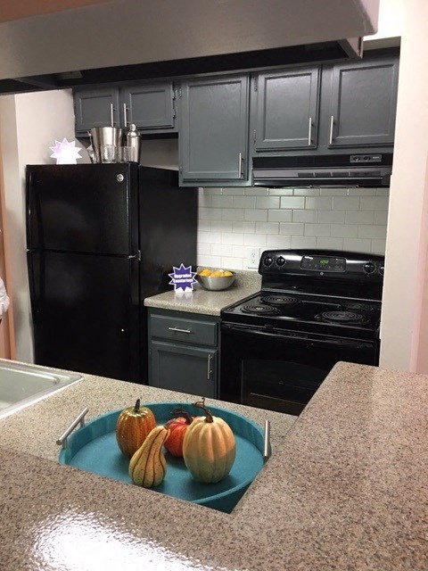 a kitchen with black appliances and a blue plate with pumpkins