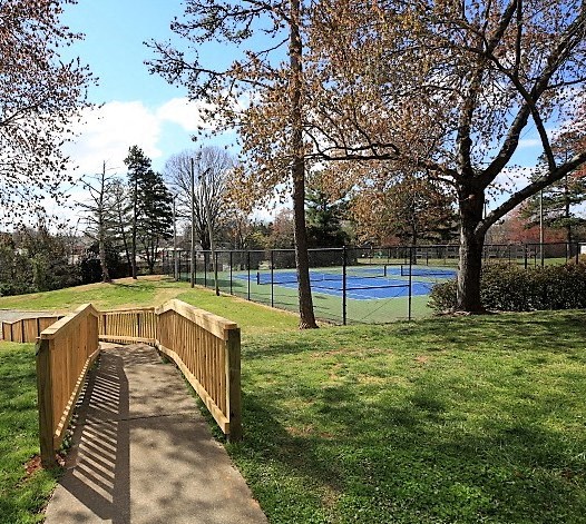 a wooden bridge in a park next to a tennis court