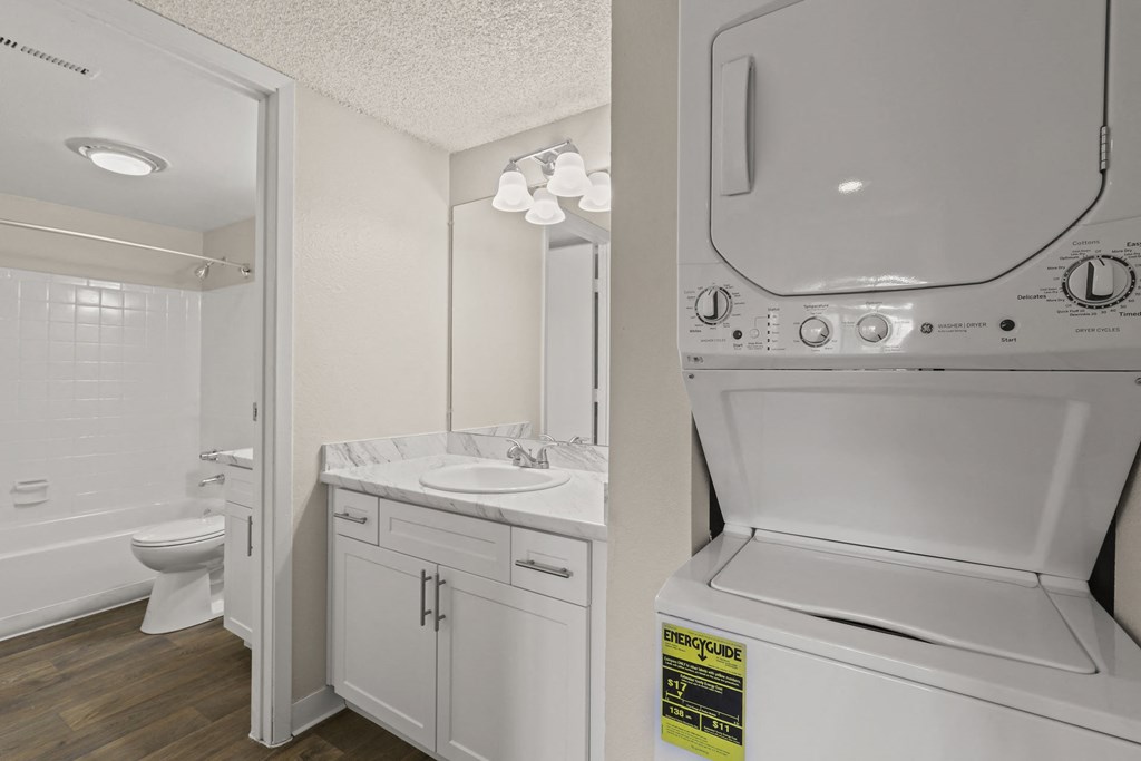 a white laundry room with a washer and dryer and a sink