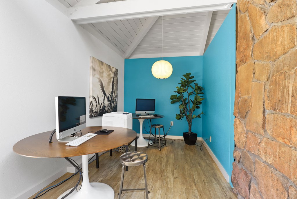 a home office with a computer on a table and a brick wall