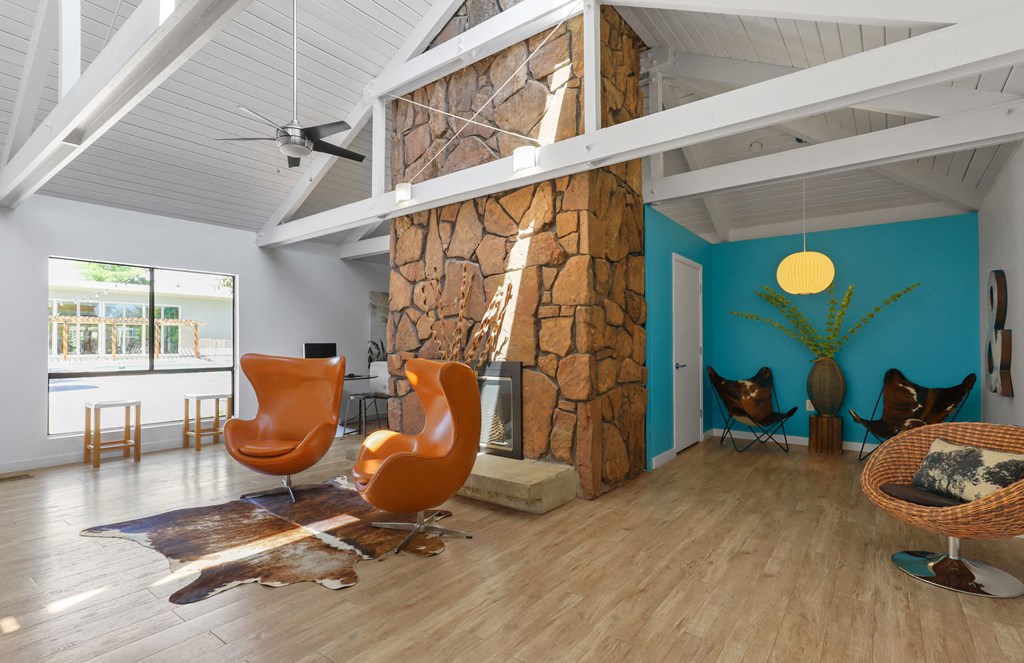 a living room with a large stone wall and chairs