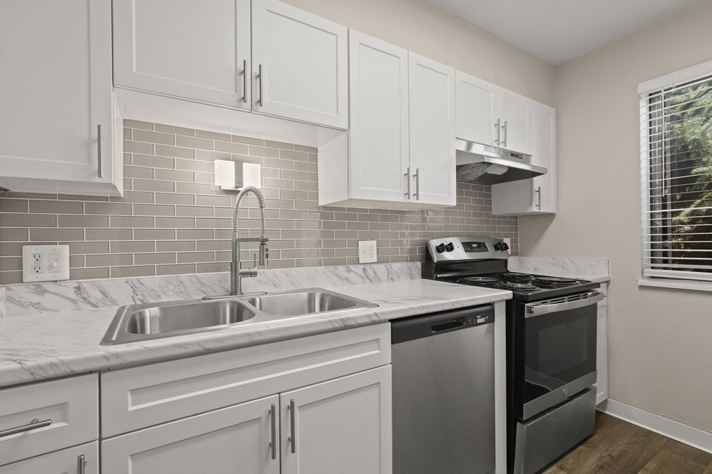 a kitchen with white cabinets and a stove and sink