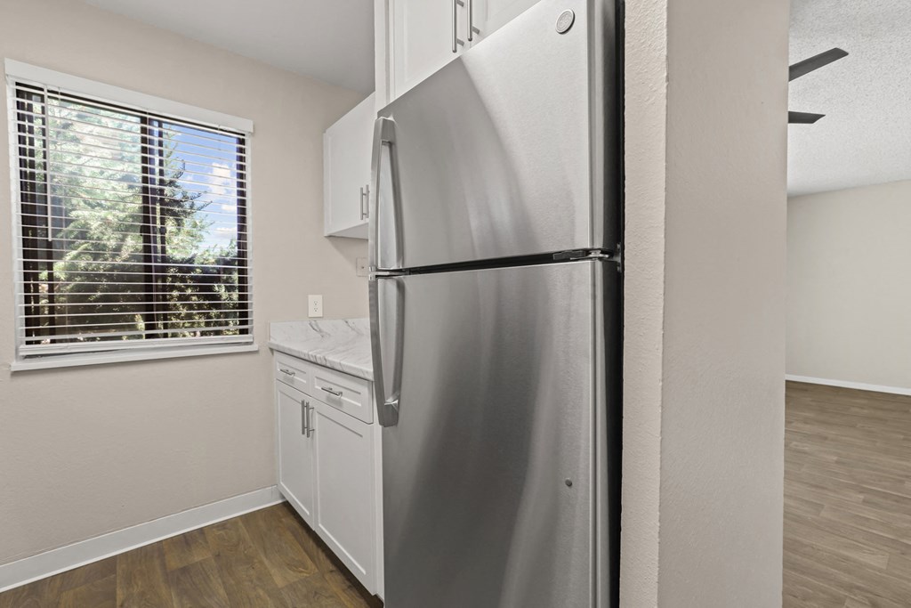 an empty kitchen with a refrigerator and a window