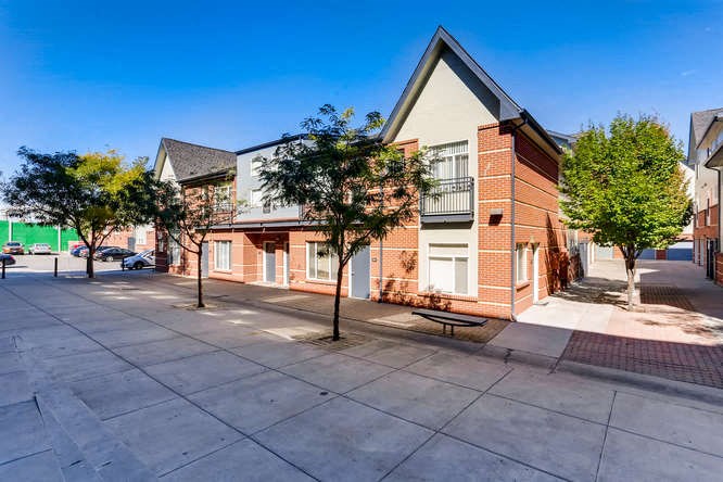 the front of a brick building with trees on the sidewalk