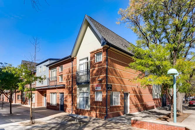 a brick apartment building with trees and a blue sky