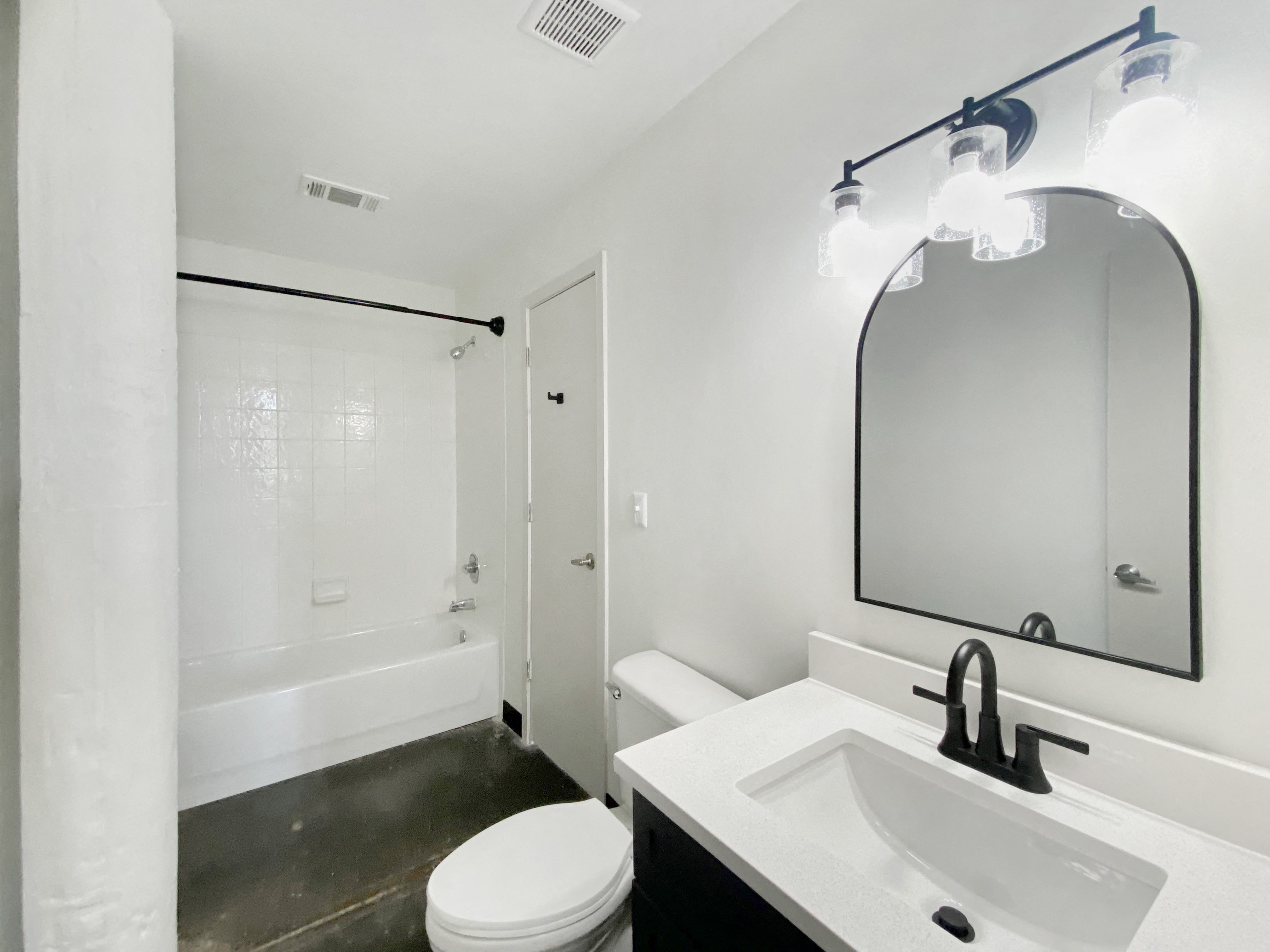 Renovated bathroom with designer lighting, polished concrete floors and bathtub