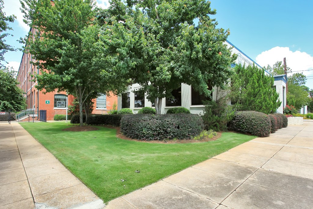 the front of a building with a lawn and trees