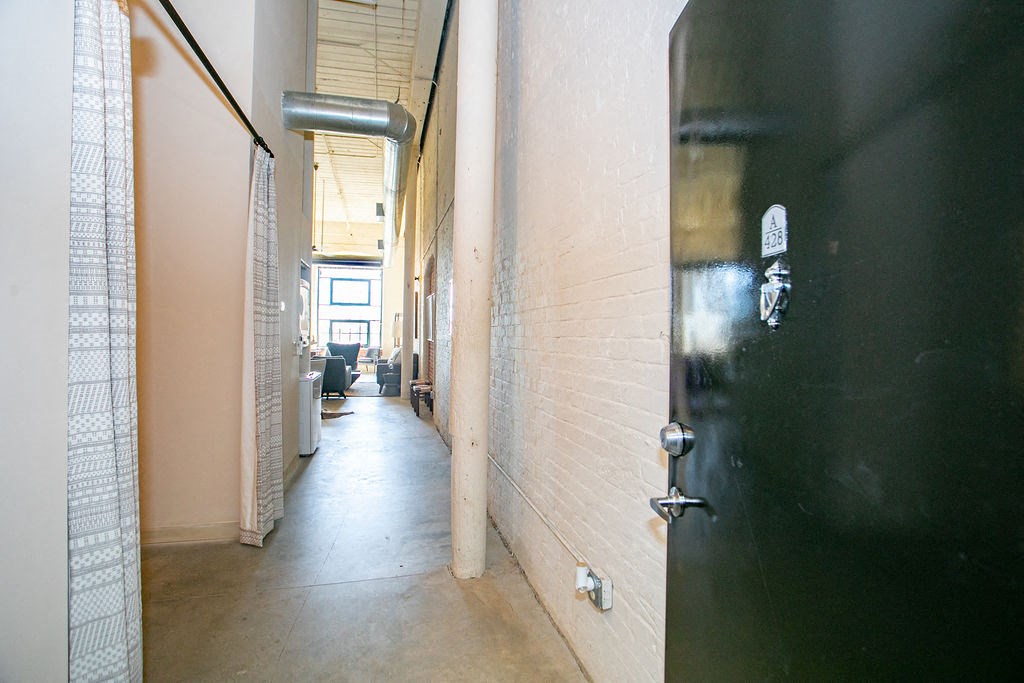 a hallway with a black door and a white brick wall