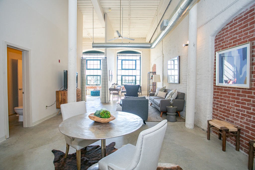 a living room with a table and chairs and a brick wall