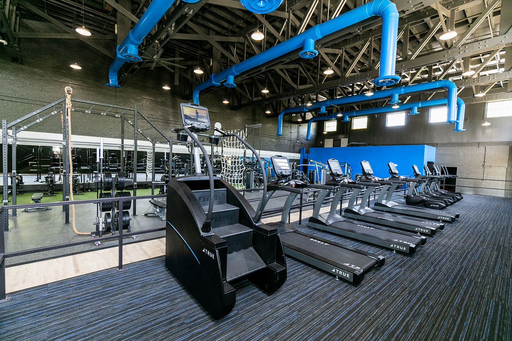 a gym with cardio machines and weights on the floor