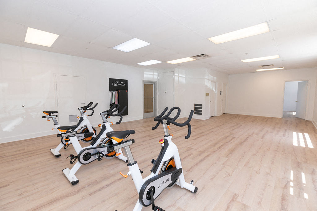 the gym has a large group of exercise bikes in it