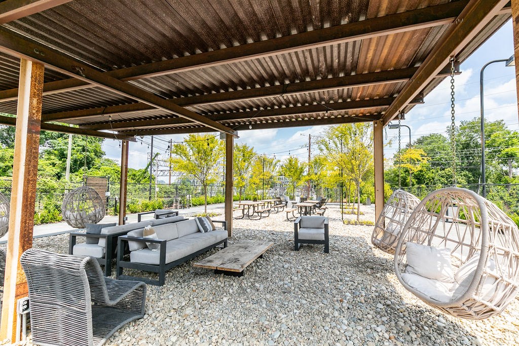 a patio with couches and chairs under a wooden roof