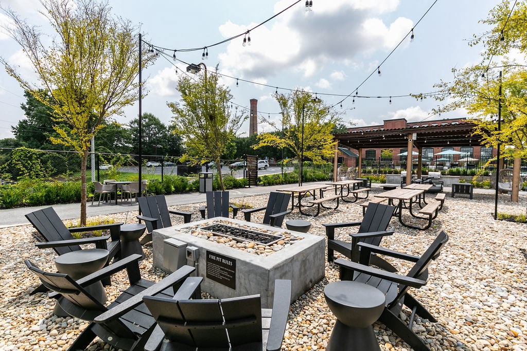 a patio with tables and chairs and a fire pit